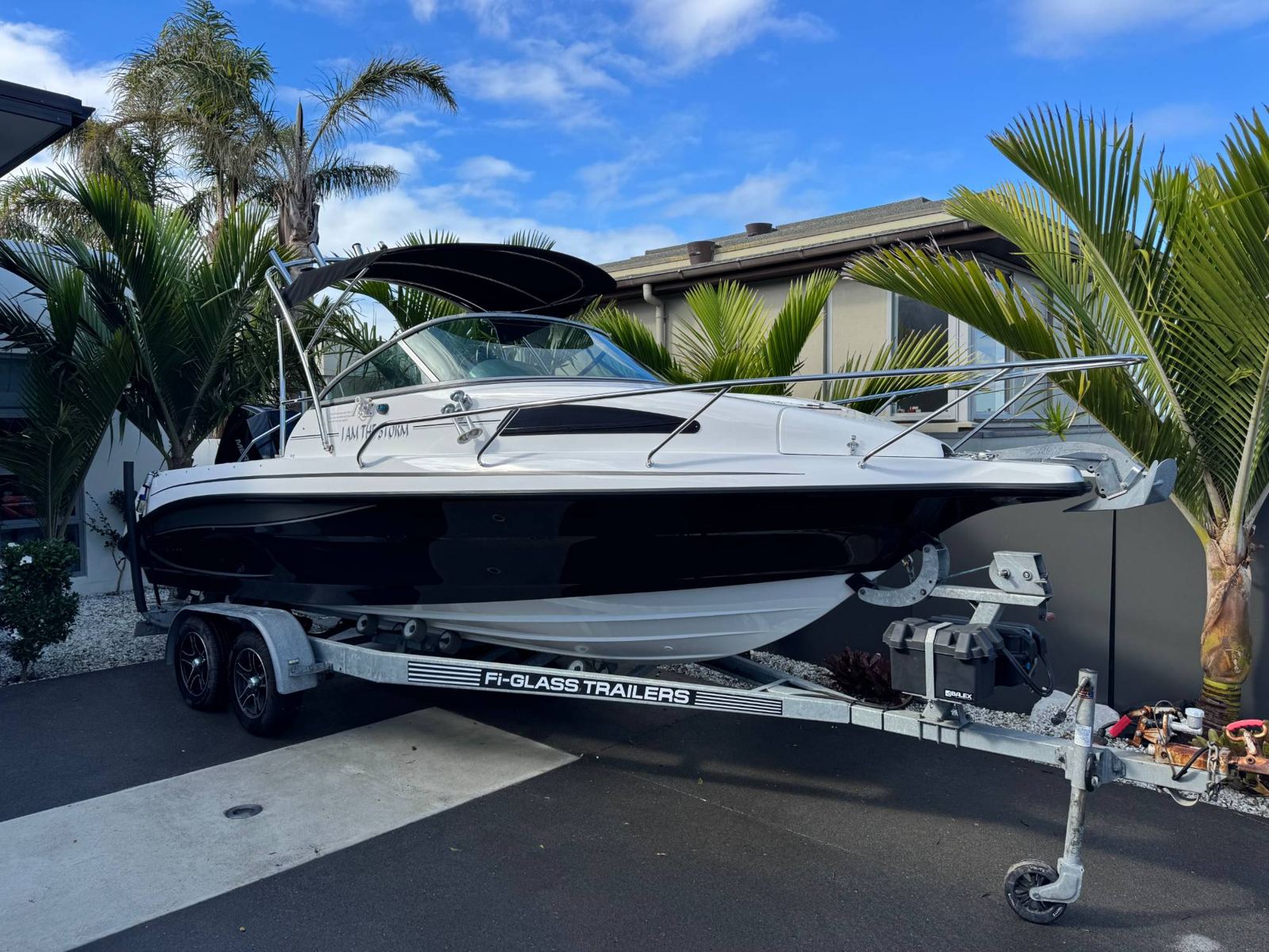 Trailer boat with glossy black hull in a driveway